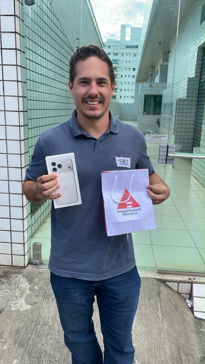Cliente segurando caixa de iPhone e sacola da Importadora Mineira