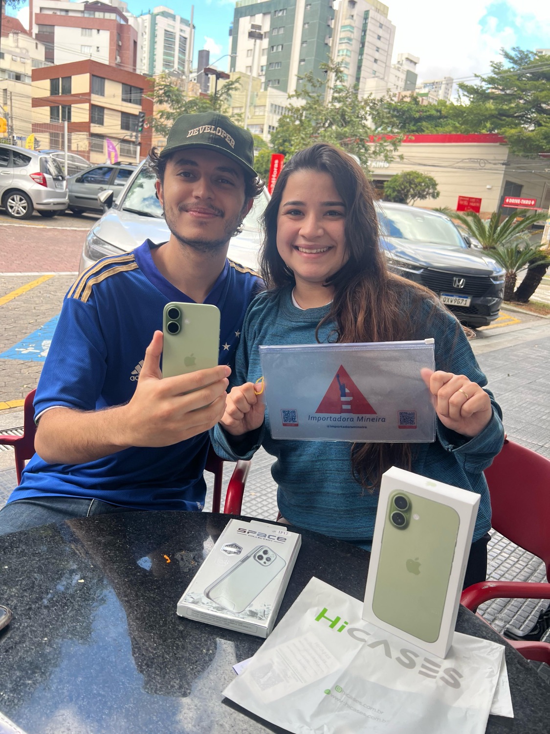 Clientes com iPhone e embalagem da Importadora Mineira em atendimento de troca